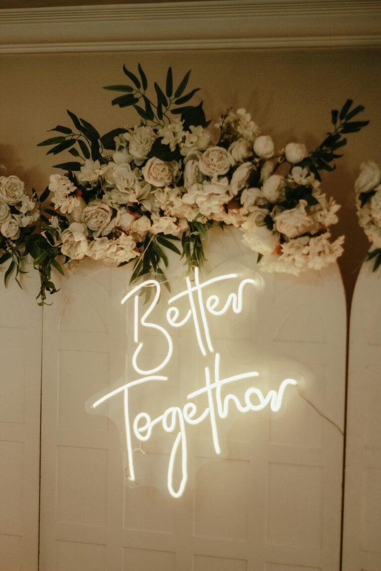 Beautiful wedding decor featuring floral arrangement and glowing 'Better Together' neon sign.