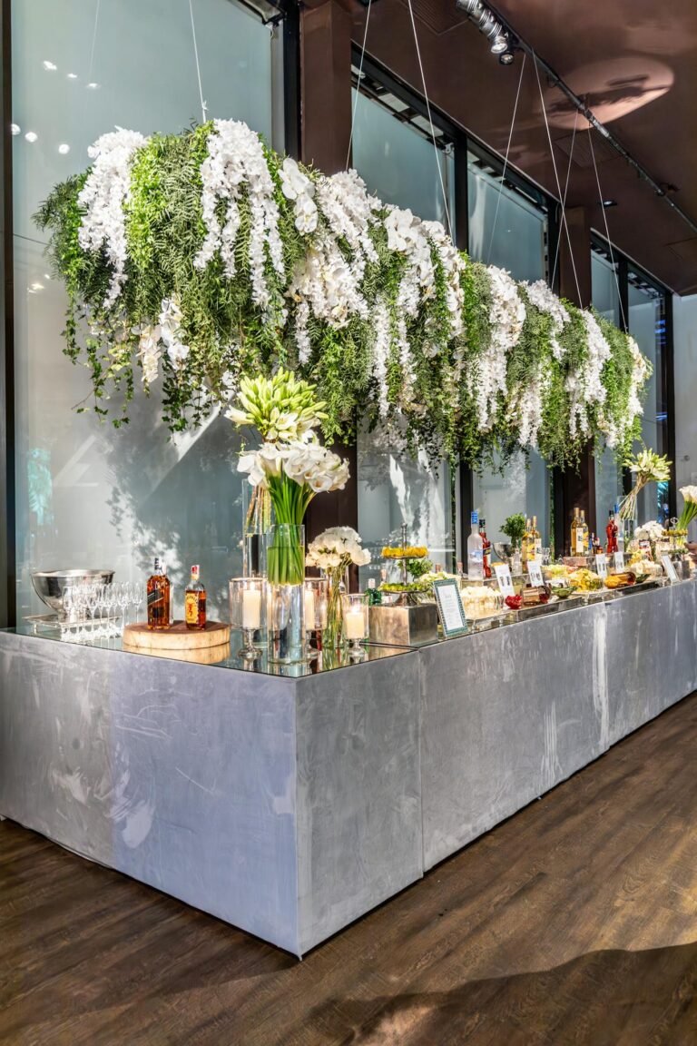 Luxurious banquet setup with hanging floral arrangements and a mirrored bar counter.