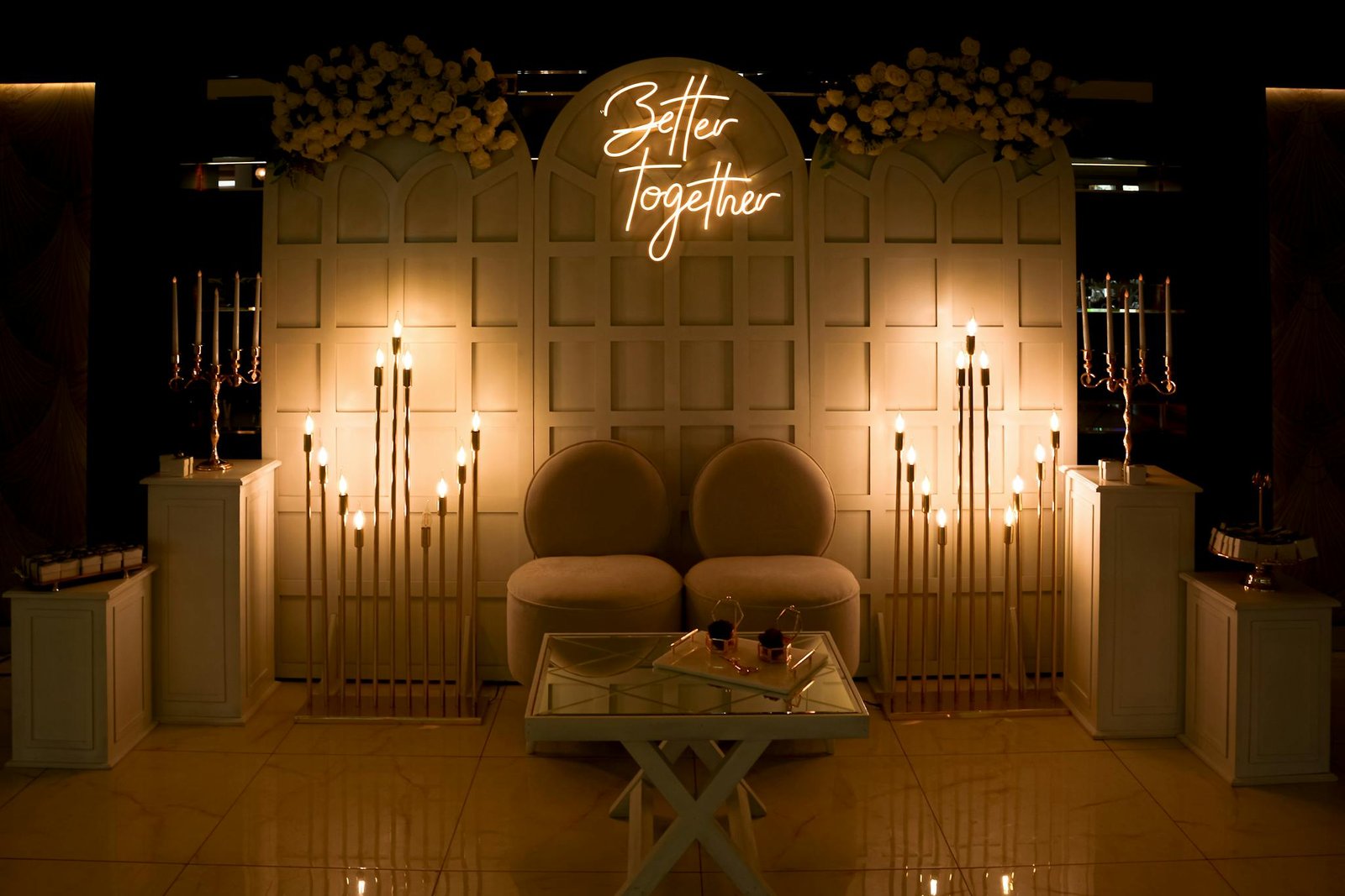 Sophisticated wedding setup featuring stylish furniture, neon sign, and ambient lighting.