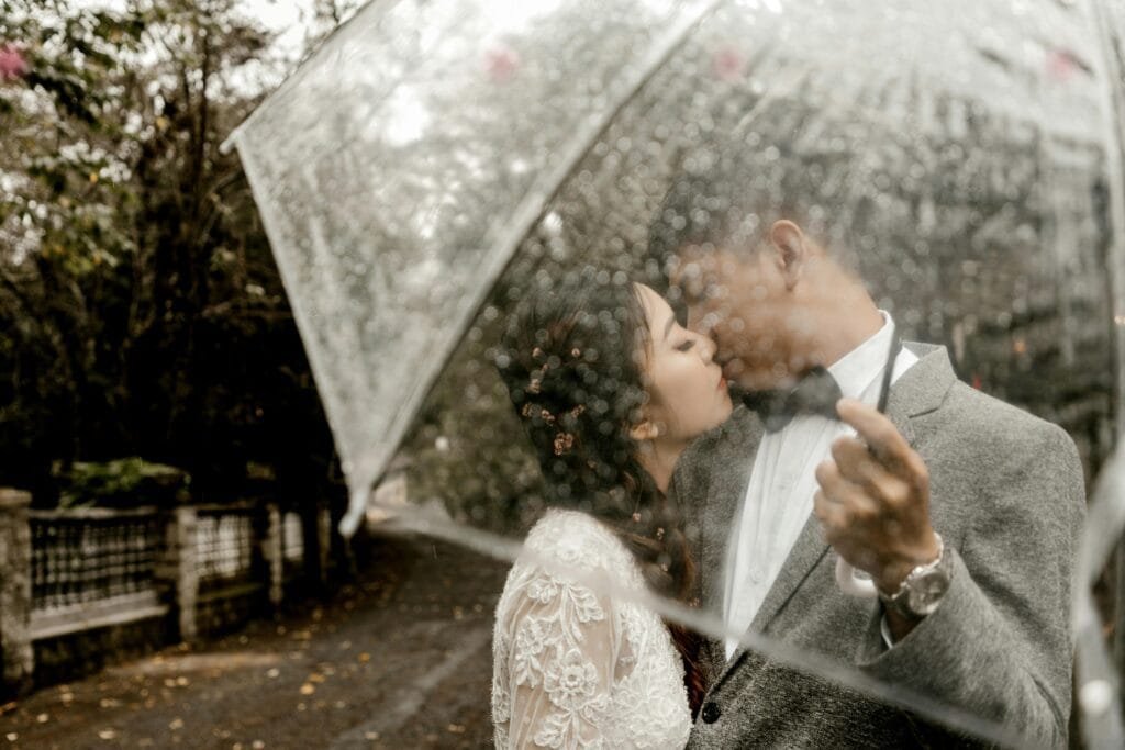 Wedding couple in the rain Bride and Groom under a clear umbrella in the rain