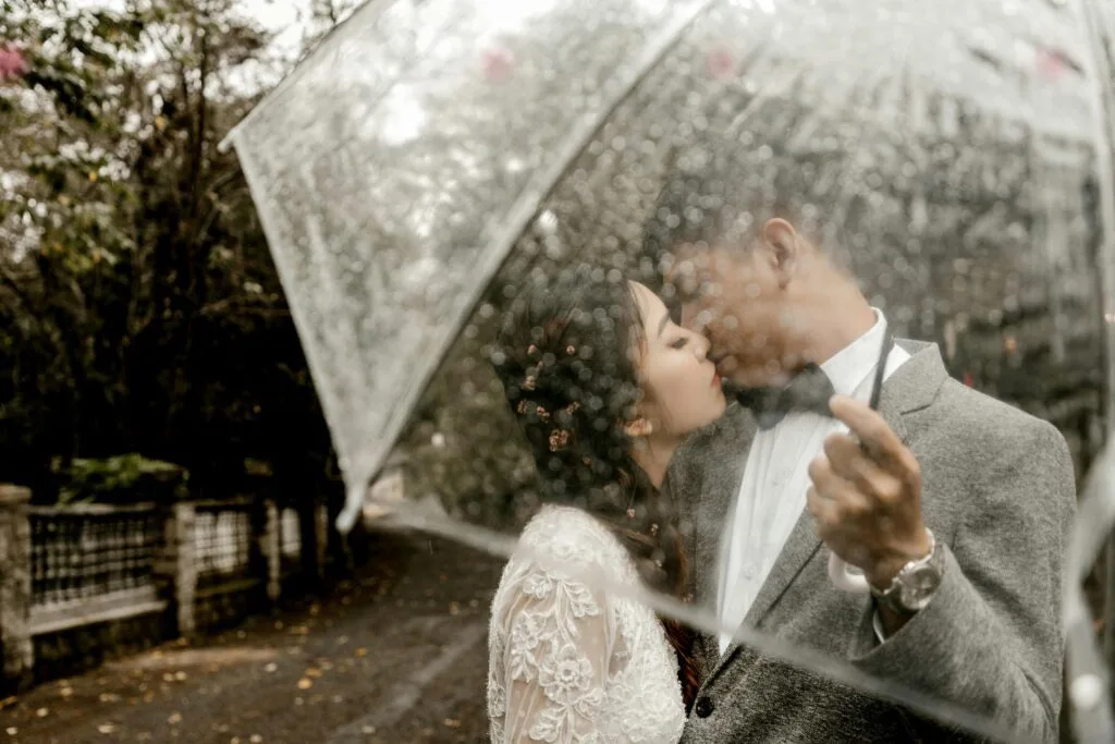 Bride and Groom under a clear umbrella in the rain